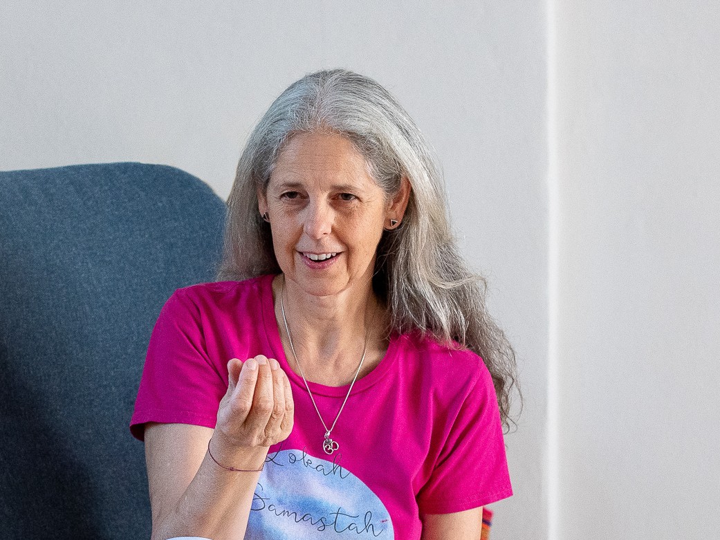 Gunda Ganga im Gespräch, sitzend in einem Sessel, gestikulierend mit der Hand während einer Online-Begleitung für Frauen