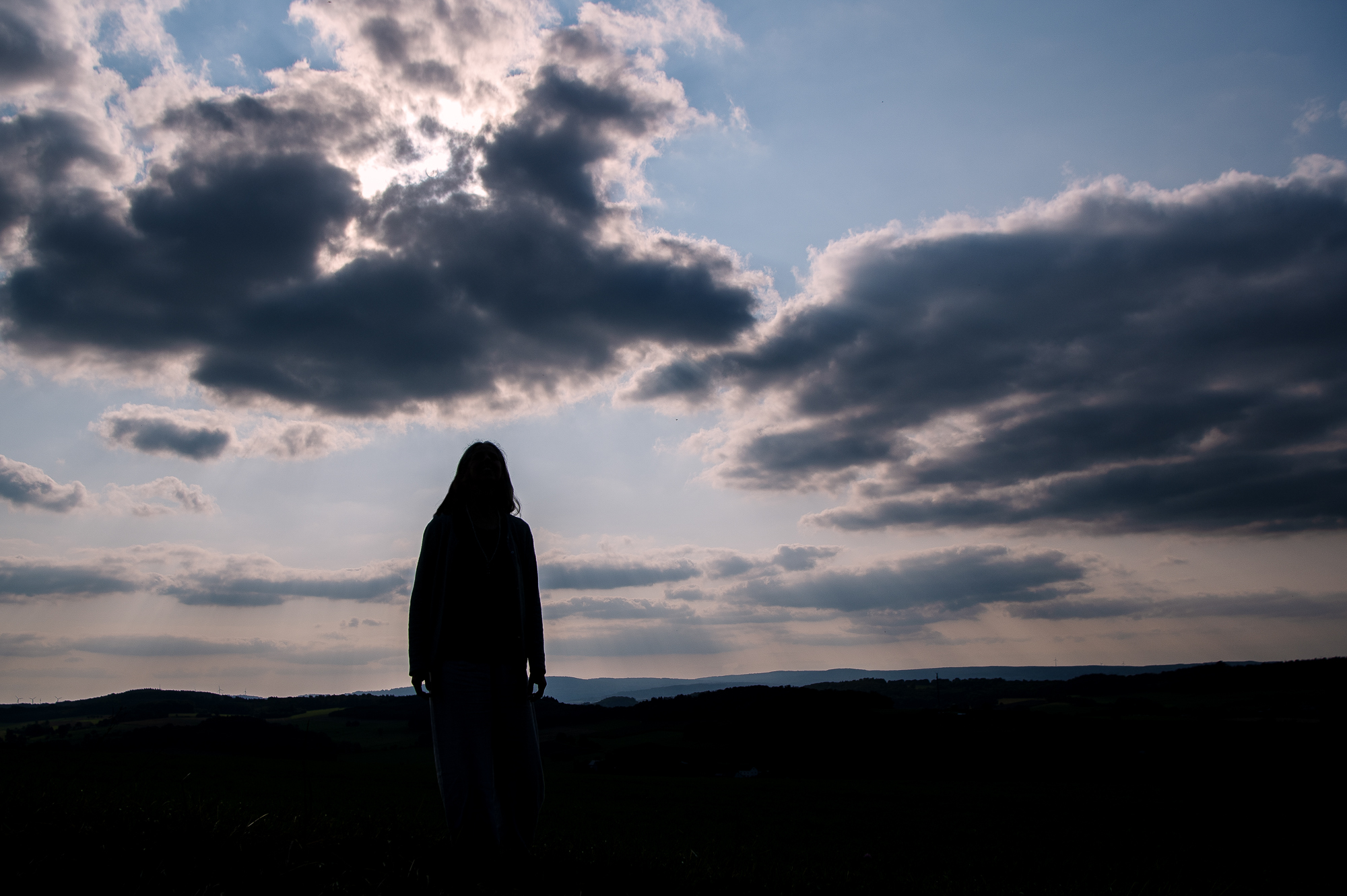 Silhouette einer Frau vor einem Himmel in der Dämmerung als Sinnbild für eine Schwelle